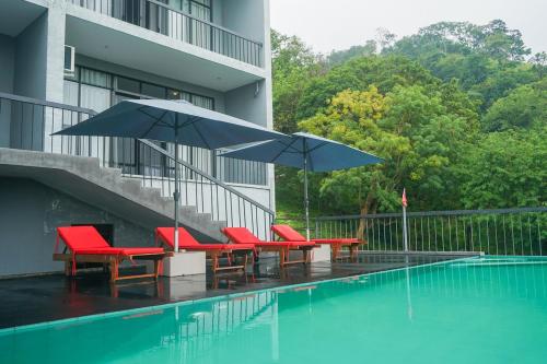 a group of chairs and umbrellas next to a swimming pool at Victoria Hideout in Digana
