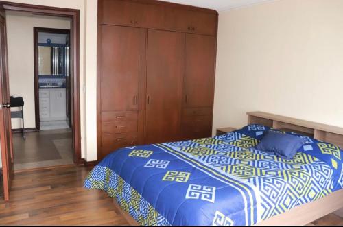 a bedroom with a bed with a blue and white comforter at Habitaciones MAAZ in Quito