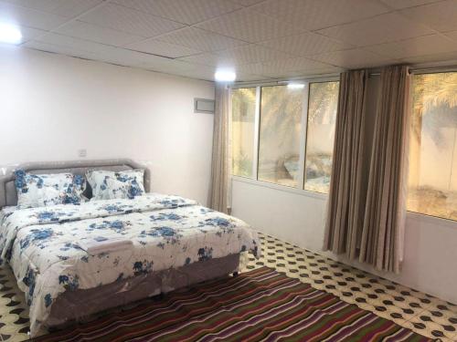 a bedroom with a bed and windows and a rug at Haret Nizwa hostel in Nizwa