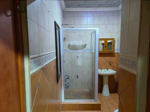 uma casa de banho com uma cabina de duche em vidro e um lavatório. em No 12 em Rustenburg