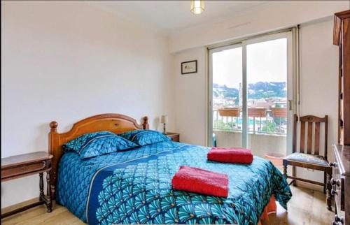een slaapkamer met een bed met een blauw dekbed en een raam bij Spacious Apartment in Vallauris for Art Lovers in Vallauris