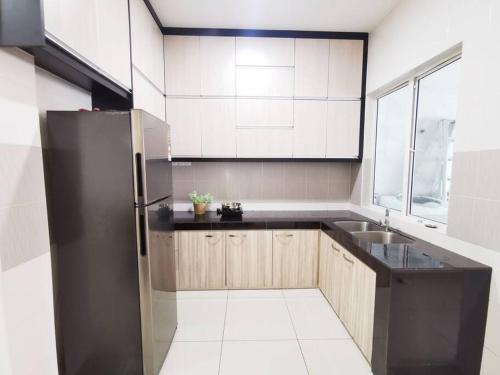 a kitchen with a black refrigerator and a sink at Bdr Seri Botani ipoh-nordic (tvbox/mahjong 19pax) in Ipoh