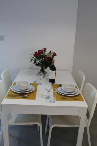 a white table with plates and glasses and a bottle of wine at Brand New Studio with Sea View in Gibraltar