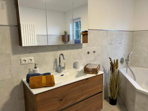 ein Badezimmer mit einem Waschbecken, einer Badewanne und einem Spiegel in der Unterkunft Ferienwohnung Landliebe in Rudolstadt