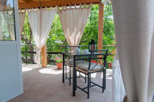 una mesa y una silla en un patio con cortinas en B&B Duino Stella Maris en Duino
