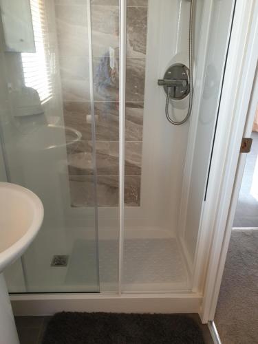 a shower with a glass door in a bathroom at Kimadalyn in Forfar