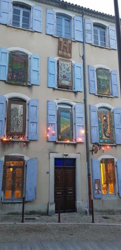 a building with blue shuttered windows and a door at Chez Albert et Karine in Sauve
