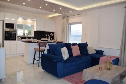 a living room with a blue couch and a kitchen at Seafront Luxury Apartment in Amfilochía