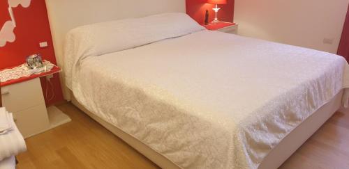 Cama blanca en habitación con pared roja en Monteceneri 9 B&b, en Rho