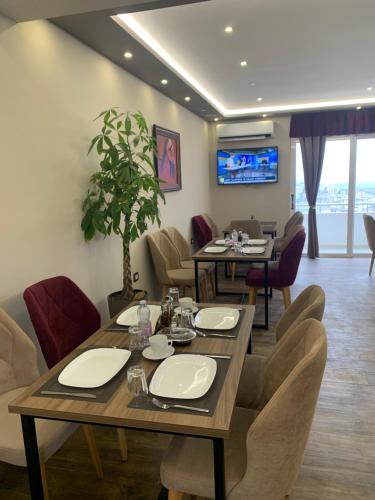 una sala da pranzo con tavolo, sedie e TV di Vladimir Estate Hotel a Gjirokastër