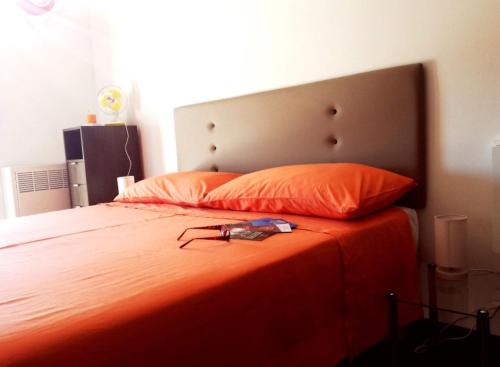Una cama con colcha naranja y un par de zapatos. en Appartamento Velocipede en Cervignano del Friuli