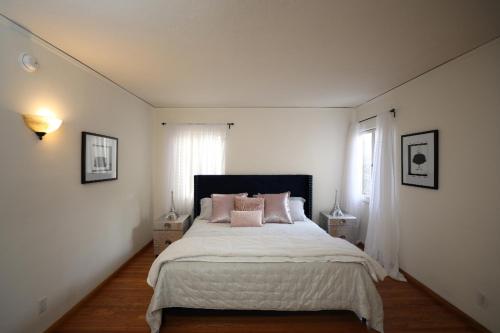 a white bedroom with a large bed with pink pillows at Renovated Spanish 3BD 2BA near Beverly Hills in Los Angeles