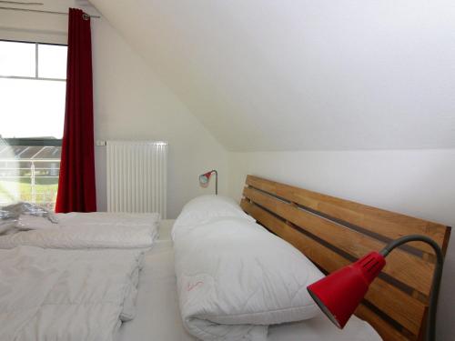 a bedroom with two beds and a red curtain at Komfortables Ferienhaus in Friedrichskoog-Spitze in Friedrichskoog-Spitz