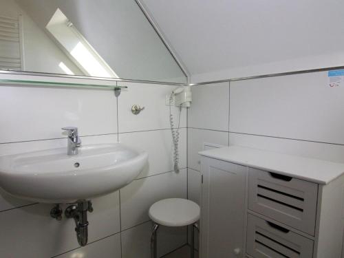 een badkamer met een wastafel, een spiegel en een kruk bij Holiday home, Friedrichskoog-Spitze in Friedrichskoog-Spitz