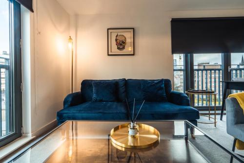 a living room with a blue couch and a table at City View - A Stunning 2 Bed Apartment in Glasgow