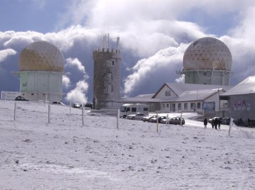 a building with two domes in the snow with people walking in front at Chalé de Montanha com sons de rio in Cortes do Meio