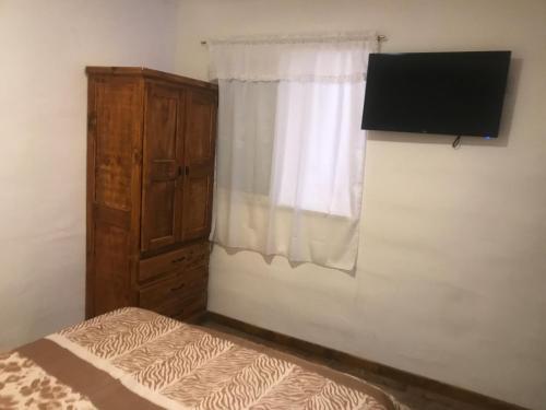 1 dormitorio con 1 cama, TV y ventana en Mageeva Miramar Bs As Argentina Departamentos en Miramar