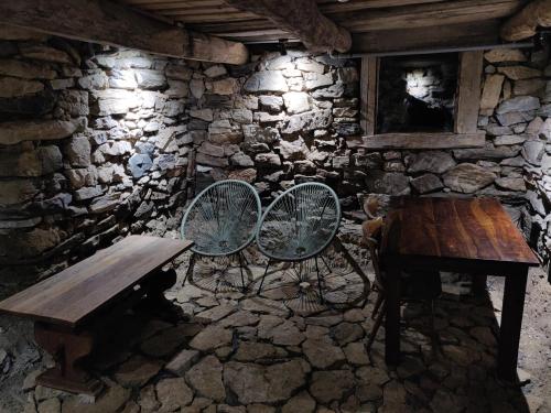 a stone room with a wooden table and two chairs at Casa Padureana - Log House from 1860 in Hunedoara