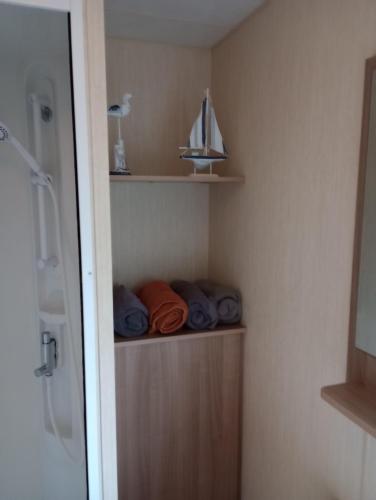 y baño con armario con toallas y lavamanos. en A22 is a 3 bedroom caravan on Whitehouse Leisure Park in Towyn near Abergele with decking and close to sandy beach en Conwy