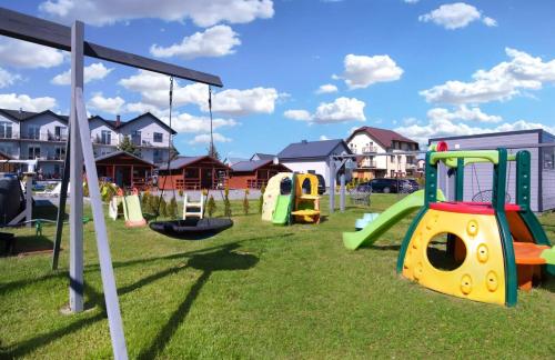 um parque infantil com escorregas e baloiços na relva em Willa Alexandria - Domki, Apartamenty, Pokoje z Basenem em Karwia