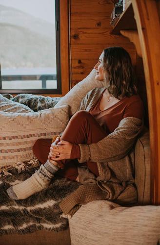 a woman sitting on a bed looking out a window at Backeddy Resort and Marina in Egmont