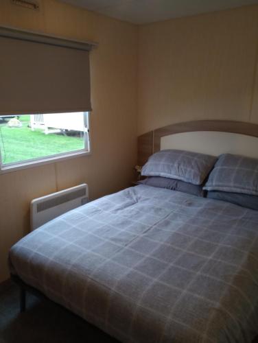 a bedroom with a large bed with a window at A22 is a 3 bedroom caravan on Whitehouse Leisure Park in Towyn near Abergele with decking and close to sandy beach in Conwy