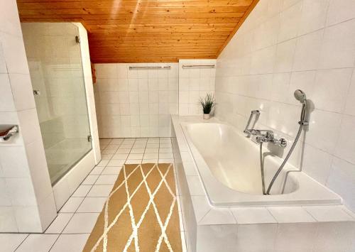 y baño blanco con bañera y ducha. en Ferienhaus Weißachdamm am Tegernsee, en Rottach-Egern