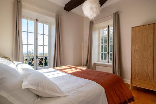 a bedroom with a large white bed with windows at Domaine Mont-Riant à Jurançon in Jurançon