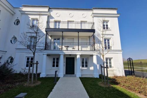 a white house with a balcony on top of it at Appartement Chic Gold - 5min Disneyland in Serris