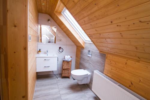 a bathroom with a white toilet and a wooden ceiling at Gościniec Tokarzonka in Istebna