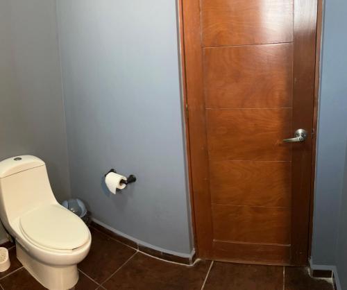 a bathroom with a toilet and a wooden door at Azul, Juriquilla Santa FE in Jurica