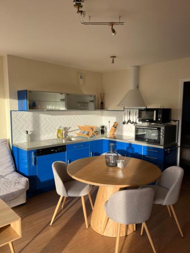 a kitchen with blue cabinets and a table and chairs at * Le Hameau de la plage * in Étables-sur-Mer