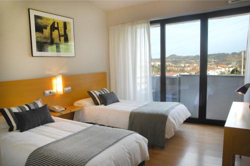 una camera d'albergo con due letti e una grande finestra di Hotel Txintxua a Hernani