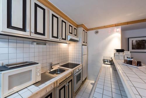 - une cuisine avec des murs carrelés blancs et des appareils électroménagers blancs dans l'établissement Appartement 3 chambres au cœur de Courchevel 1850, à Courchevel