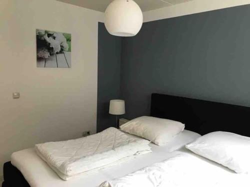 een slaapkamer met een bed met witte lakens en een lamp bij Sfeervol vakantiehuis op de Veluwe 2-6 personen in Putten
