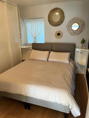 Ce lit se trouve dans une chambre dotée d'une fenêtre et d'un miroir. dans l'établissement * Le Hameau de la plage *, à Étables