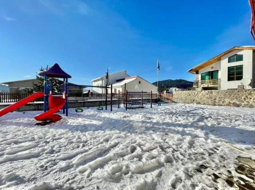 einen schneebedeckten Spielplatz mit einer roten Rutsche in der Unterkunft HORIZONT in Bakuriani