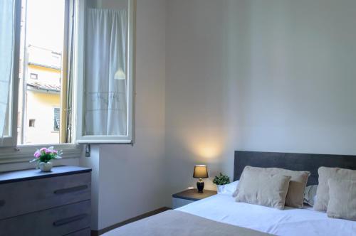 1 dormitorio con cama blanca y ventana en Homelink Firenze - Charlotte en Florencia