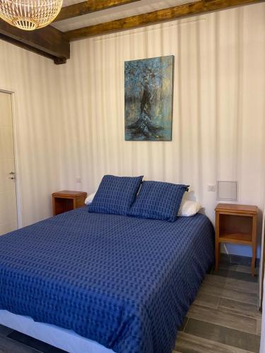 a bedroom with a blue bed and a painting on the wall at Gite bien-être hammam et jacuzzi ,sauna in La Grotte