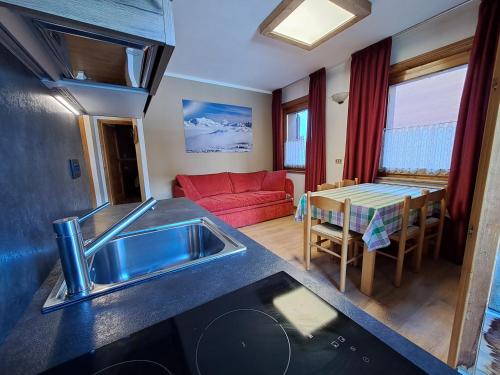 a kitchen and living room with a sink and a red couch at Casa Anita in Livigno