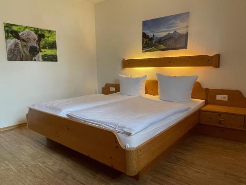 a bedroom with a wooden bed with white sheets at Landhaus Waldhauser in Schönau am Königssee
