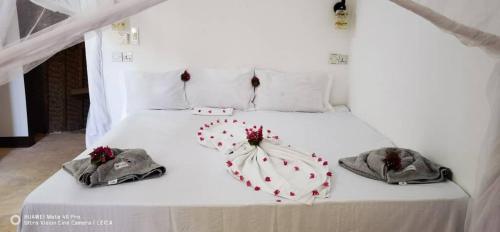 una cama blanca con dos sombrillas en forma de corazón en Wow Beach House en Jambiani
