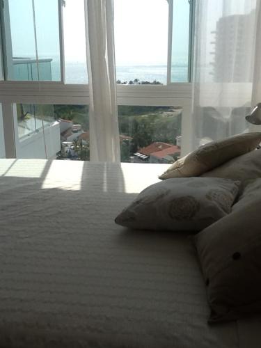 1 cama blanca con almohadas frente a una gran ventana en areia beach paradaise, en Santa Marta