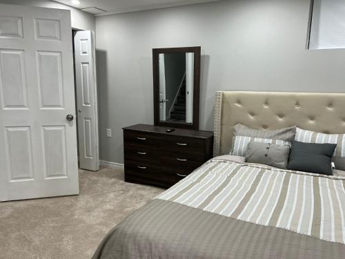 Schlafzimmer mit einem Bett, einer Kommode und einem Spiegel in der Unterkunft Hestia Unit in Kitchener