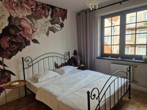 a bedroom with a bed with a flower mural on the wall at Oficyna Form - Apartament Dwupoziomowy in Elblag