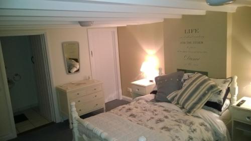 a bedroom with a bed and a dresser and a lamp at Troy House in Painswick