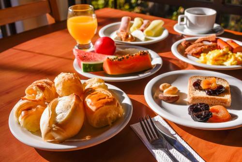uma mesa com pratos de pequeno-almoço e sumo de laranja em Monreale Resort Parque Aquático em Poços de Caldas
