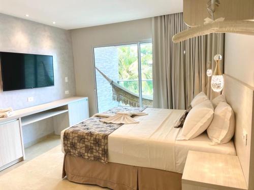 a bedroom with a large bed and a television at Pousada Maracabana Spa in Porto De Galinhas