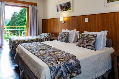 a hotel room with two beds and a window at Monreale Resort Parque Aquático in Poços de Caldas