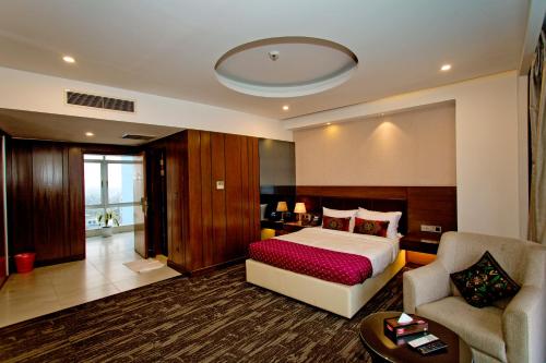 een slaapkamer met een bed, een bank en een stoel bij Jashore IT Park Hotel and Resort in Jessore